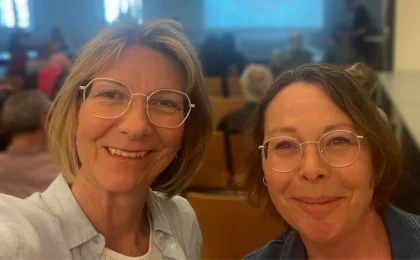 2 Frauen, Anita Zeilinger-Pferschl und Susanne Bauer, vor den Teilnehmer:innen der Generalversammlung des Alpenvereins Sektion Krems.